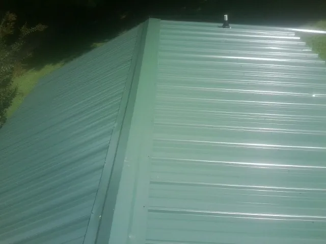 New green metal panels meeting at the ridge of a roof — Flat Roof Repair work by our crew in Allendale